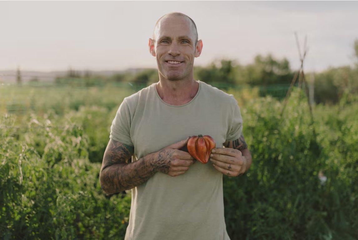 Agricultor sosteniendo un tomate en un campo verde