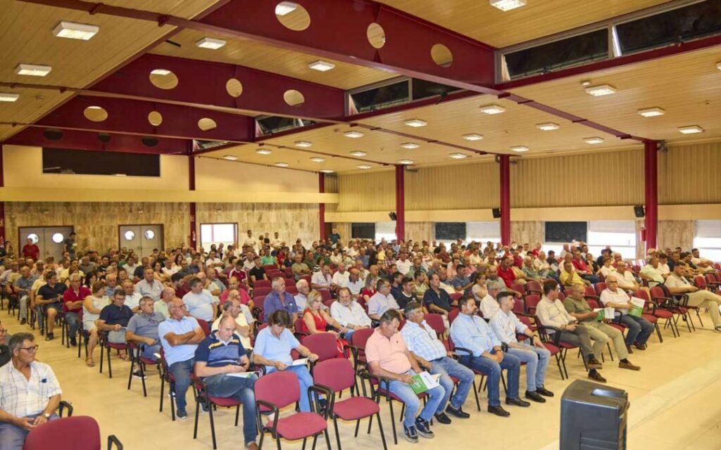 Reunión de agricultores en un salón, promoviendo el cooperativismo agrícola.
